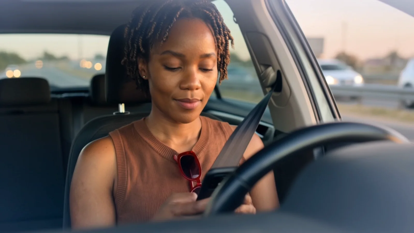 Still from the Base referral film: a woman in a car looking at the Base app on her phone